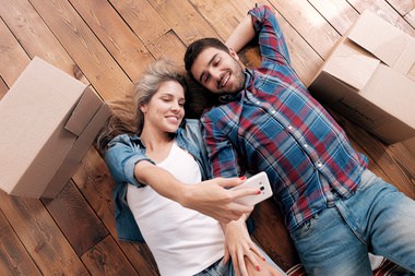 Boyfriend and girlfriend taking selfie on floor with boxes after moving into their new downtown Savannah condo