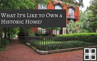 Classic historic home in Savannah, Georgia with red brick exterior, wrought-iron fence, palm trees, and a brick walkway in a tree-lined district.