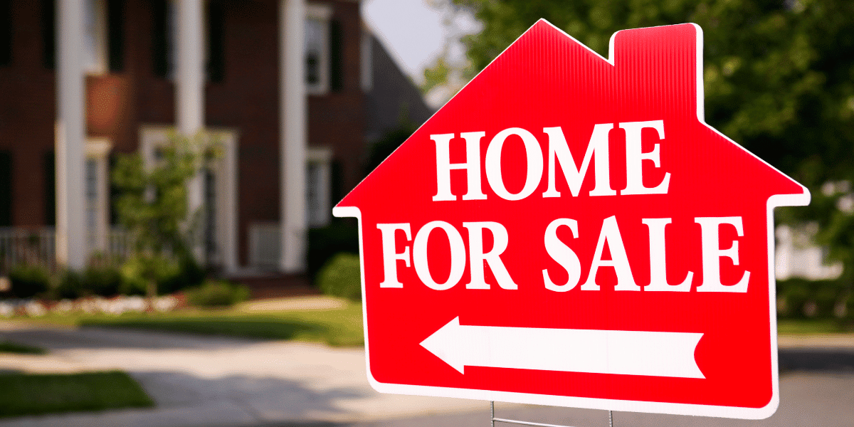 A home for sale sign in the shape of a small house