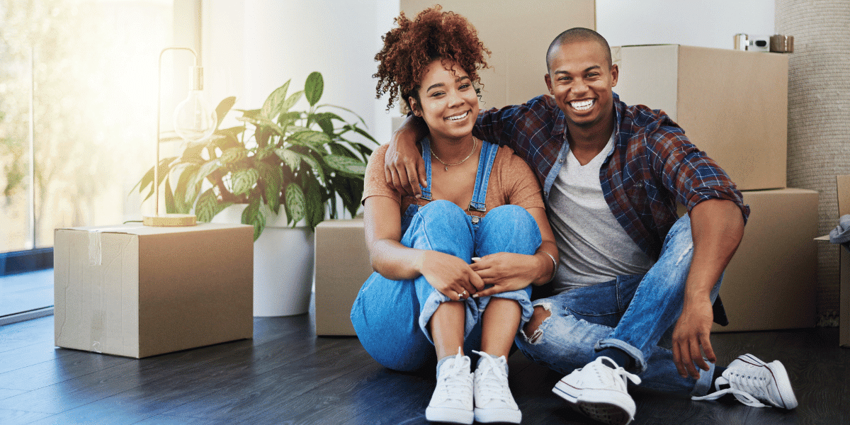 Two newlyweds surrounded by boxes who've purchased their first home together